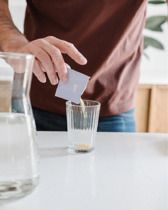homme qui verse son complément fertilité en poudre dans un verre