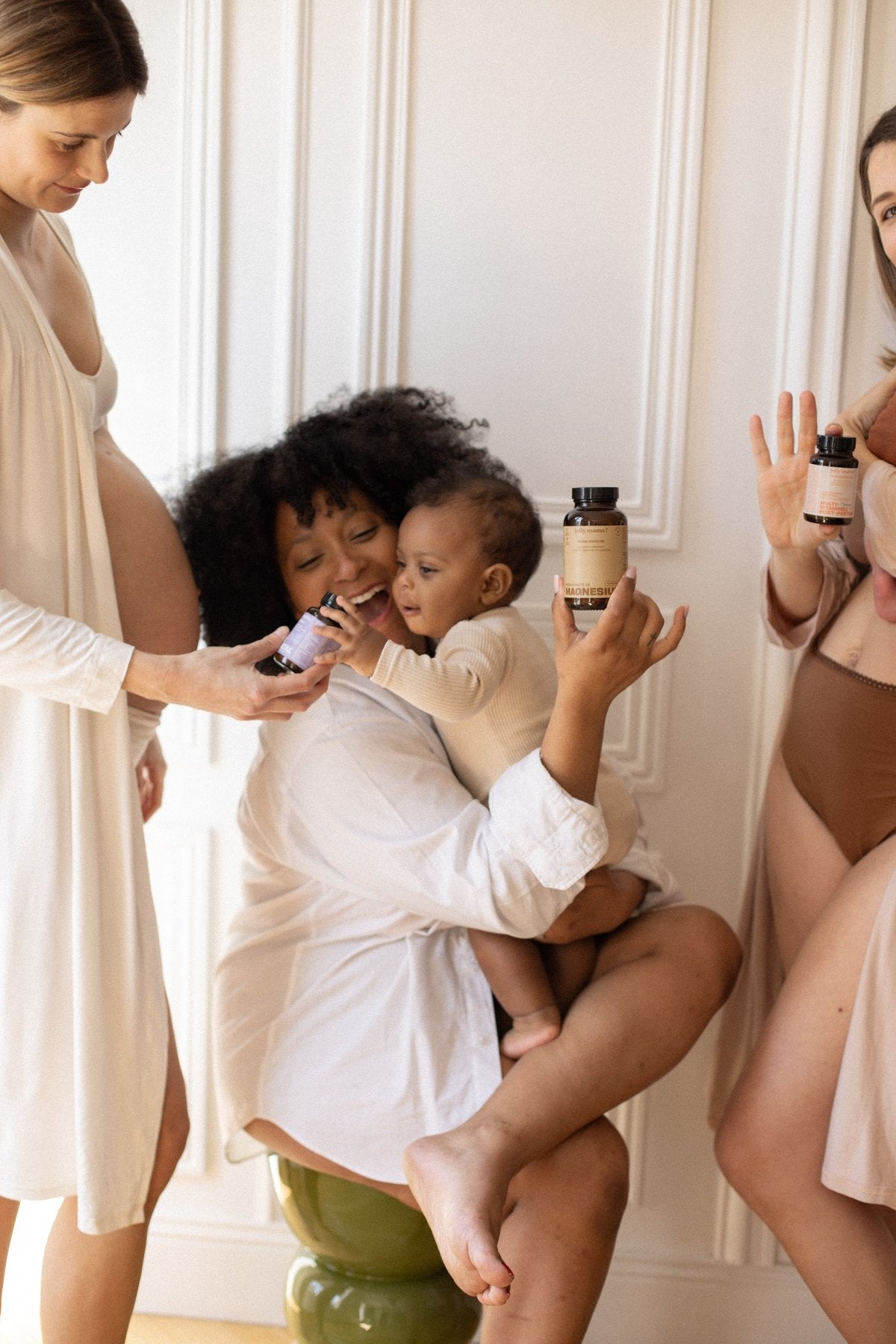 Femmes enceintes et jeunes mamans tenant des compléments alimentaires Jolly Mama, en tenue naturelle, dans un intérieur lumineux et chaleureux