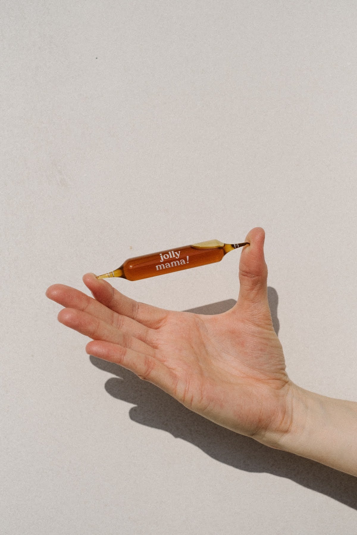 Ampoule d'un complément alimentaire développé par Jolly Mama et tenue dans une main