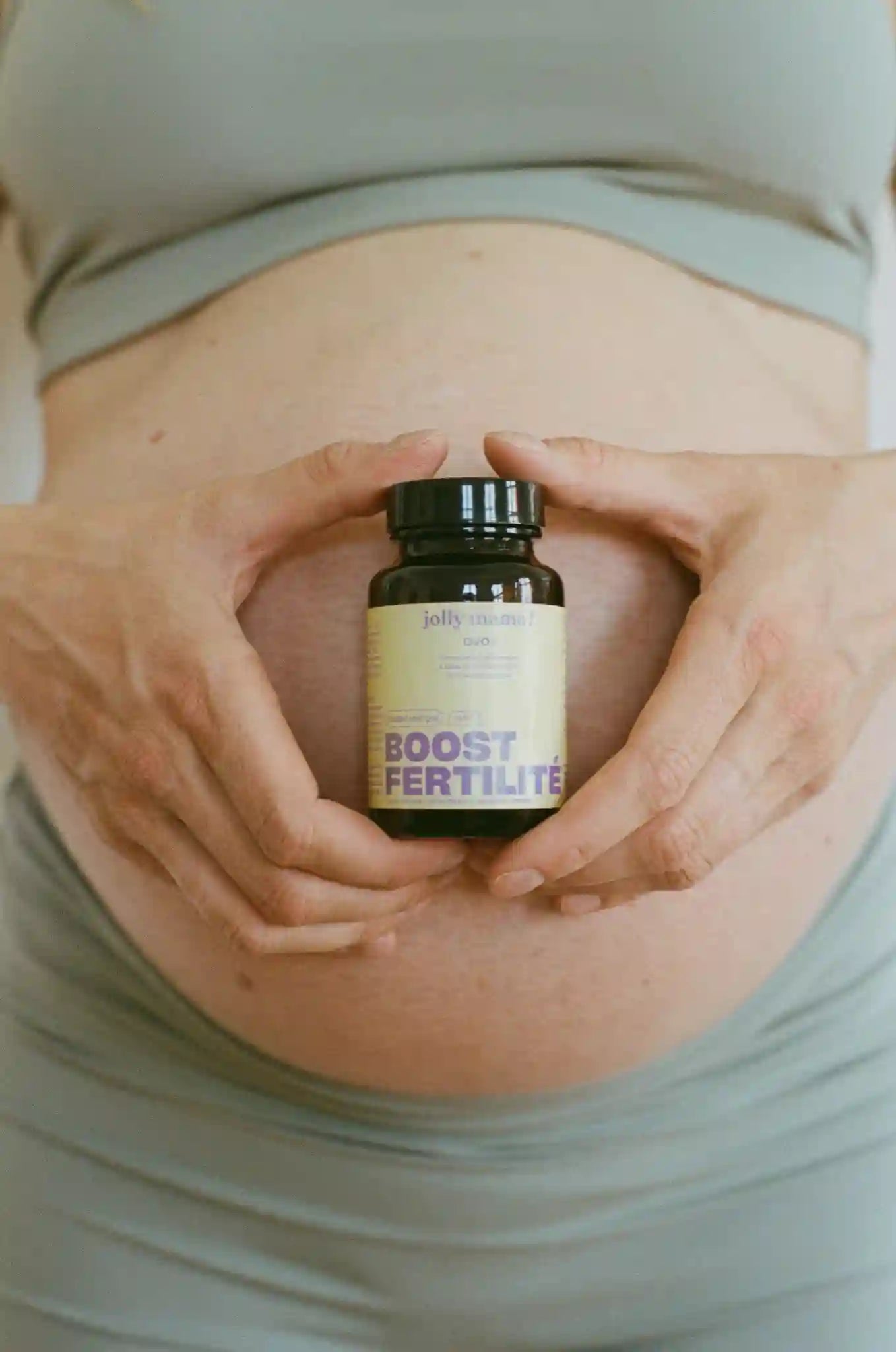 Femme enceinte  tenant un complément alimentaire Jolly Mama Boost Fertilité devant son ventre