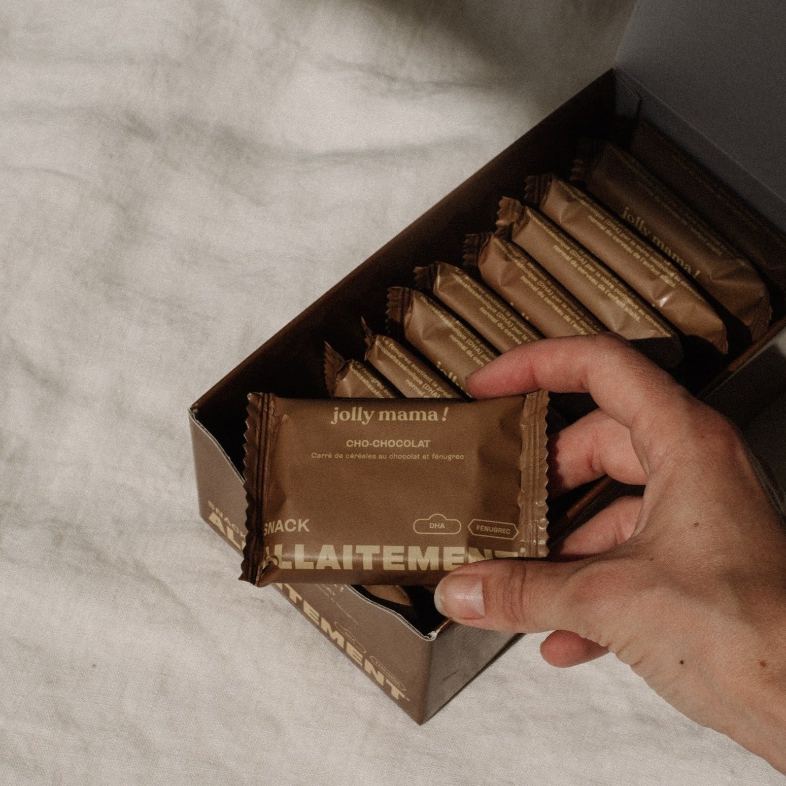 main prenant un snack allaitement Cho chocolat sortant d'une boite
