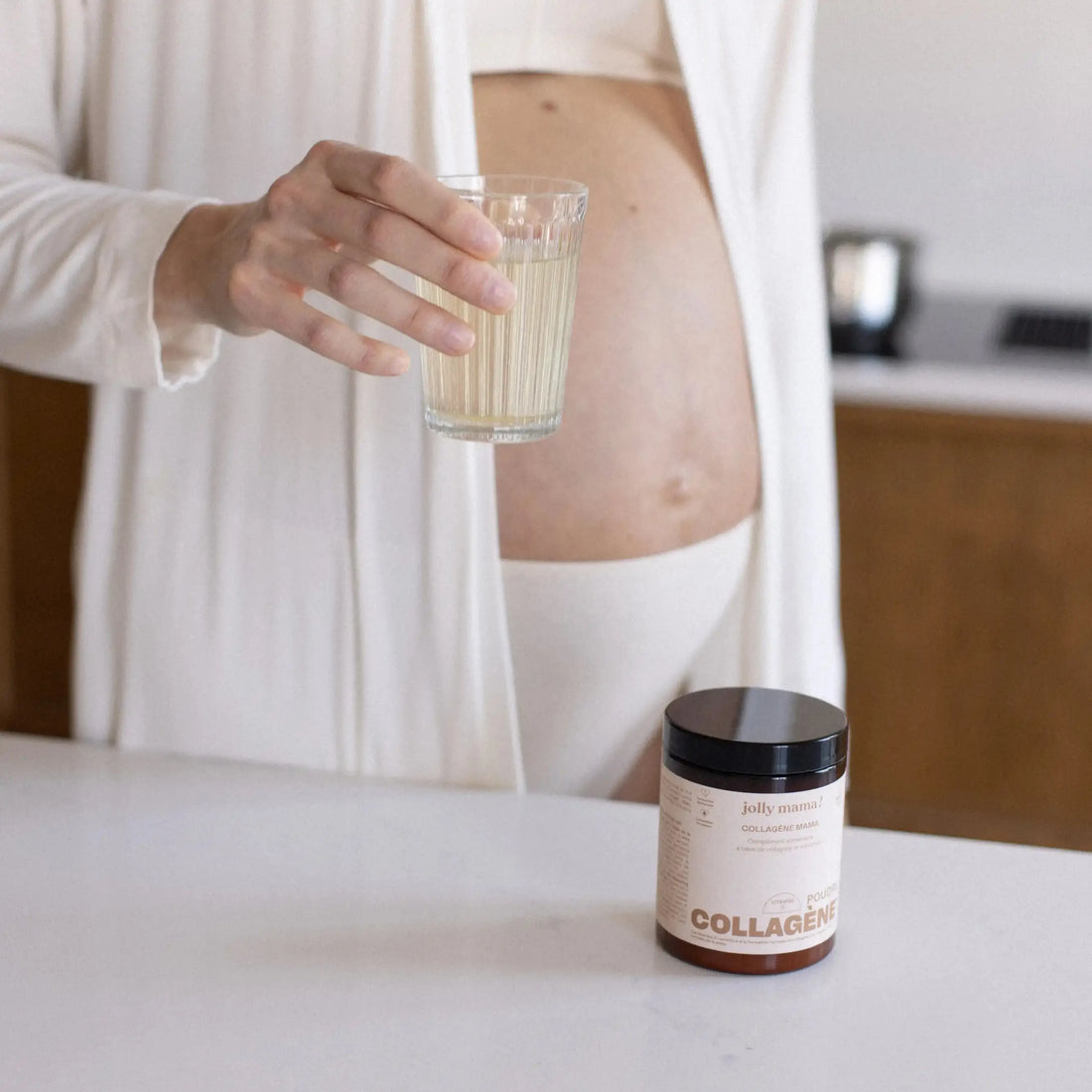femme enceinte avec un verre de collagène mama et le pot en premier plan