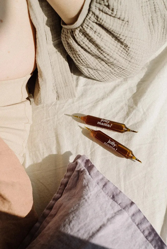 Deux ampoules mama dreams posées sur un lit dans une lumière apaisante – complément pour favoriser un sommeil réparateur chez les femmes enceintes, jeunes mamans ou en période de stress.