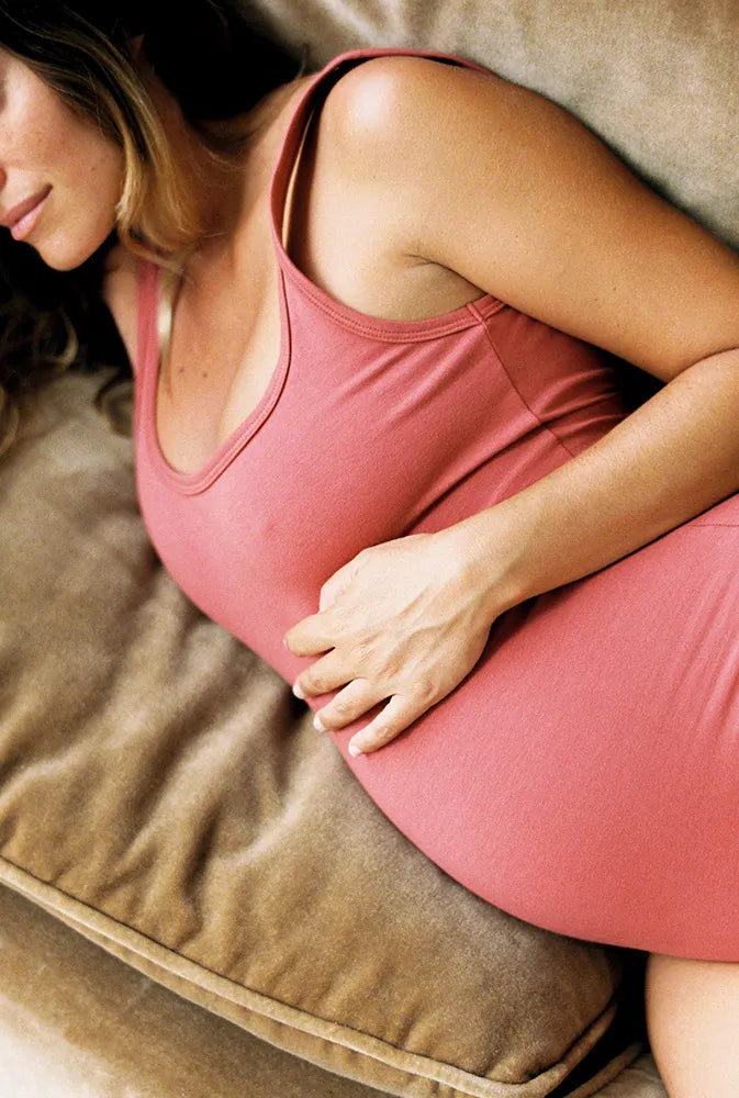 Femme enceinte allongée sur un canapé, main posée sur son ventre rond – image paisible illustrant le besoin de vitamines B6 pendant la grossesse pour soulager les nausées et soutenir l’énergie.
