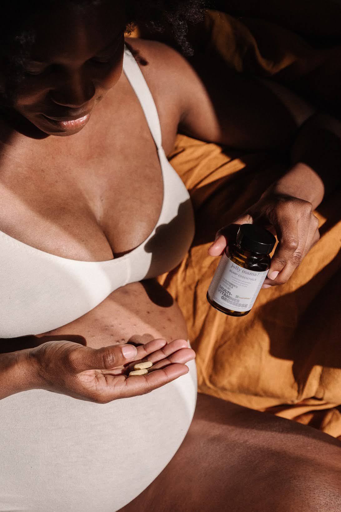 Femme enceinte prenant deux gélules de complément multivitamines grossesse