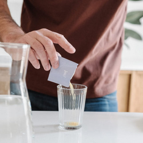 homme qui verse son sachet de complément fertilité dans un verre