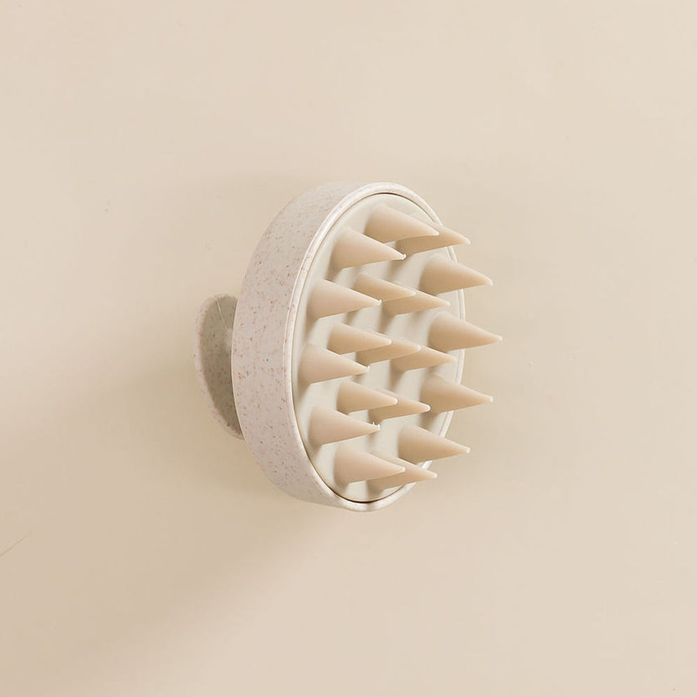 Brosse en silicone pour cuir chevelu, vue de côté, posée sur une surface. 

