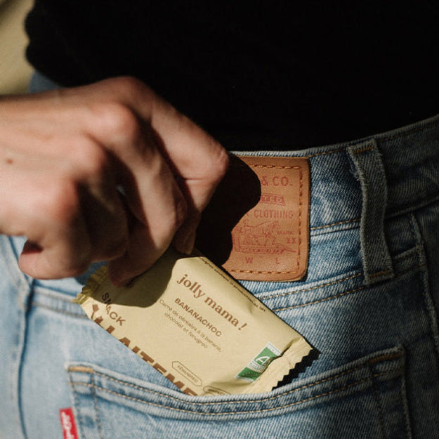 Femme sortant de sa poche un snack allaitement banane chocolat de Jolly mama